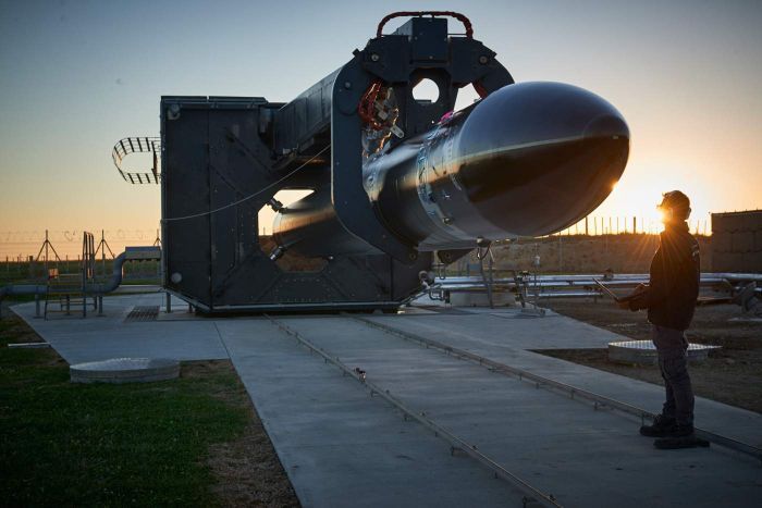 A man stands in front of a rocket getting ready for luanch